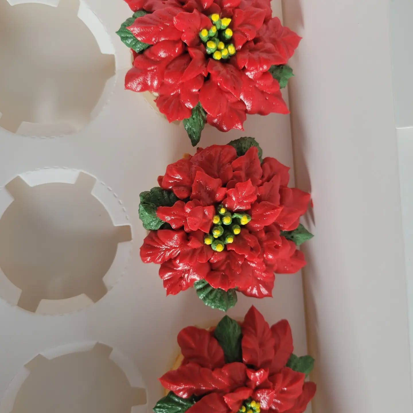 Cupcakes with white frosting and toppings on a wooden serving board; indoors, warm lighting.