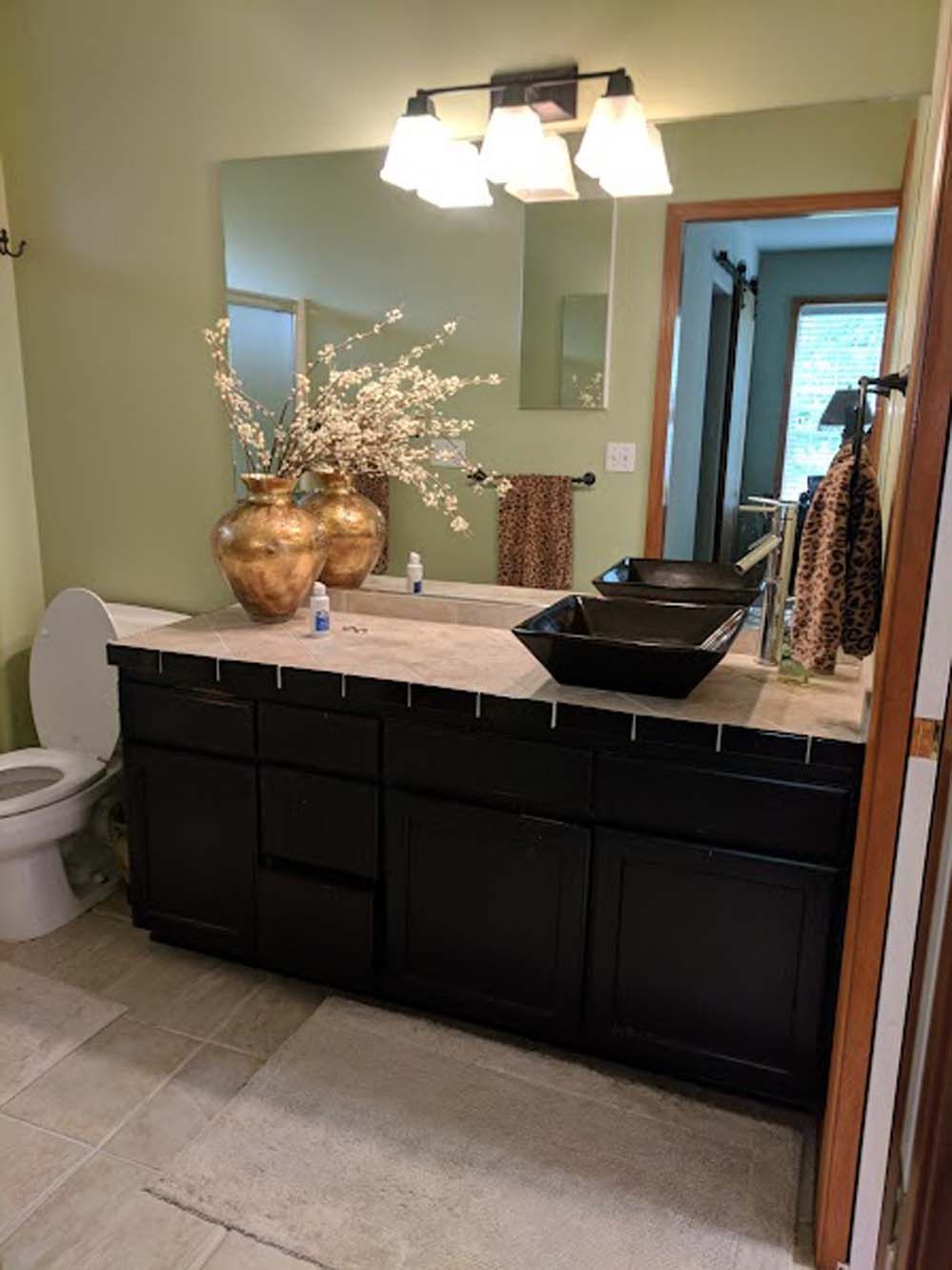 A bathroom with two sinks , a toilet and a mirror.