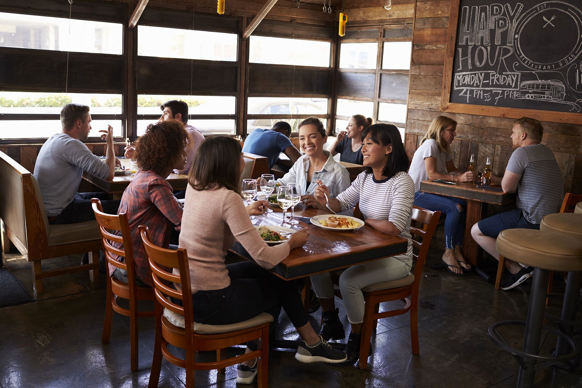 A group of people are sitting at tables in a restaurant eating food.