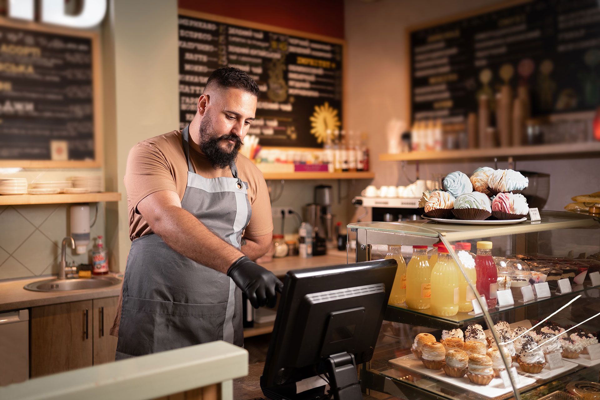 A man is standing in front of a computer in a bakery.