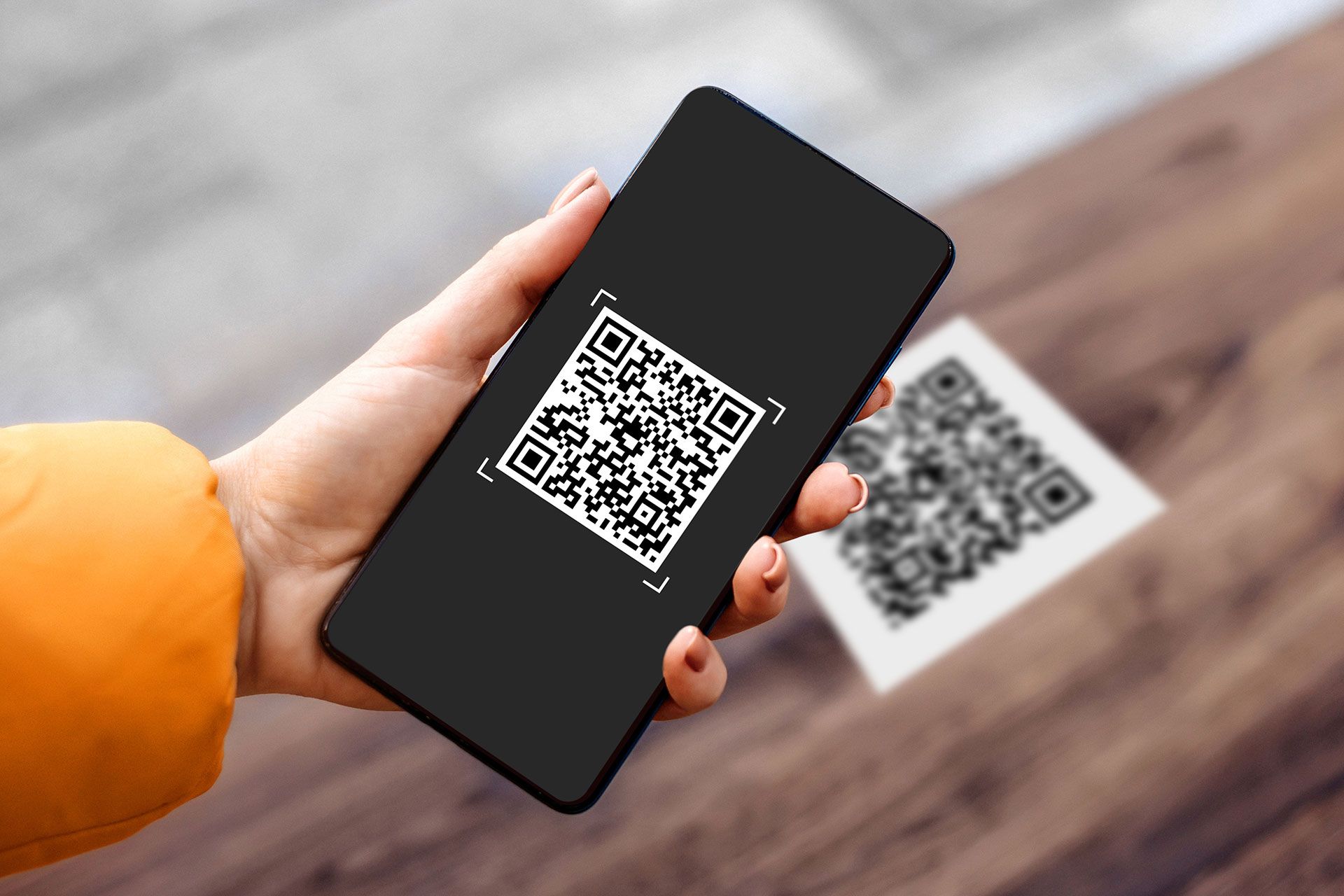 A person is holding a cell phone with a qr code on it.