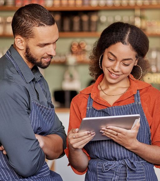 A man and a woman are looking at a tablet together.