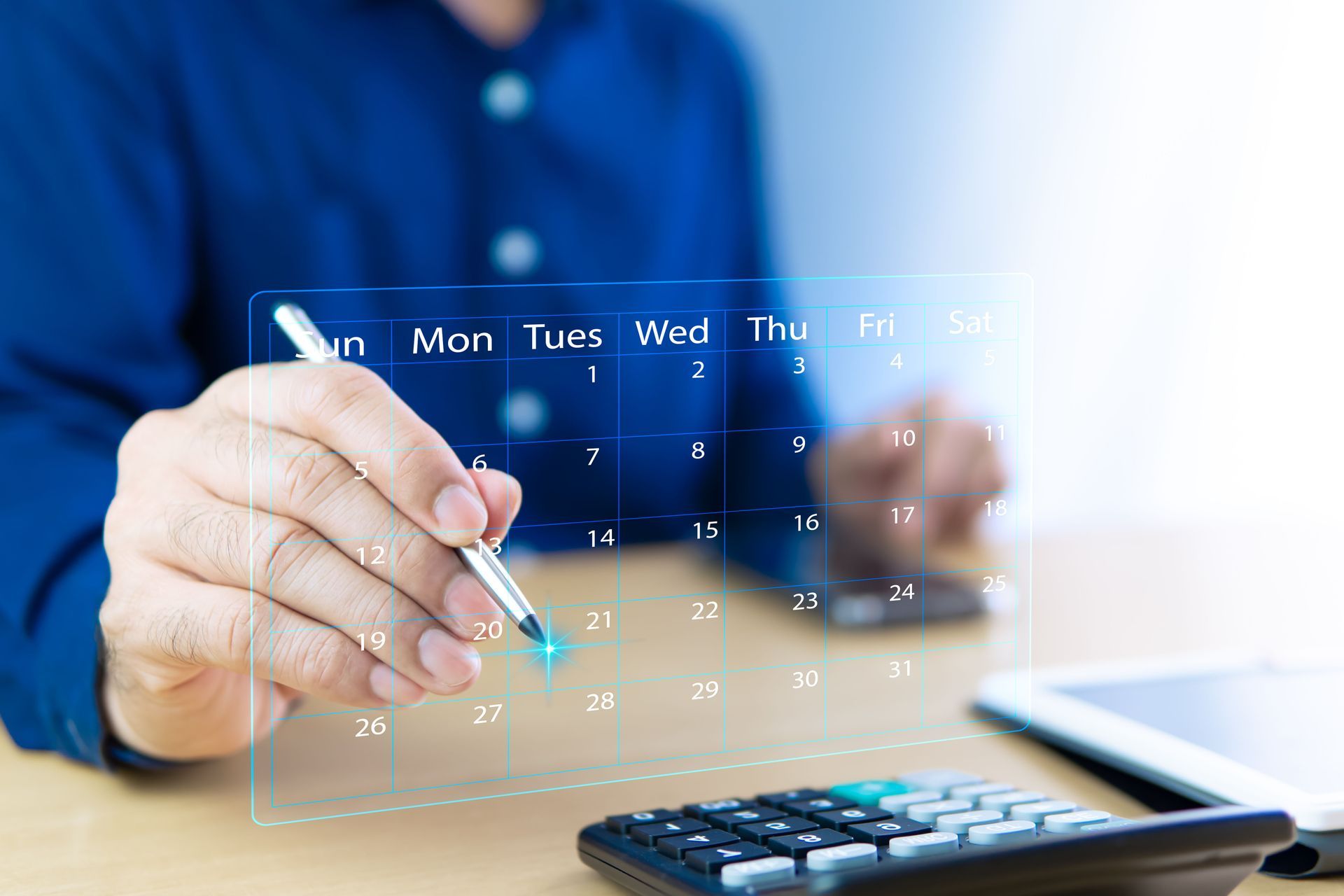 An accountant working with a virtual calendar and a calculator on his desk.