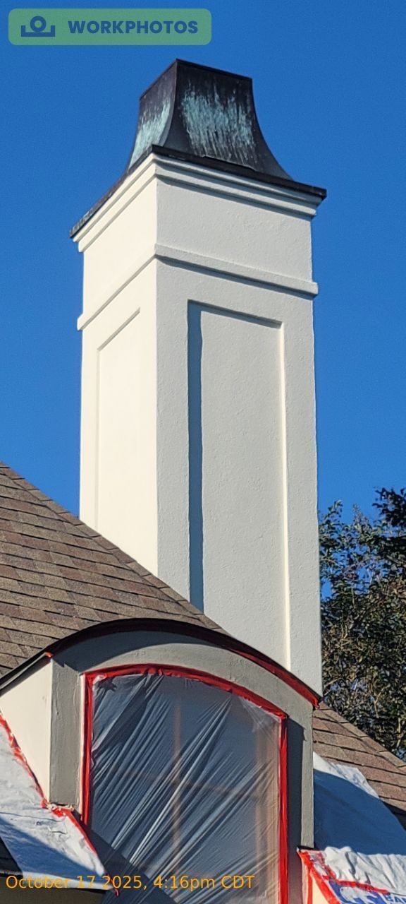 White church steeple with a dark roof against a clear blue sky, seen above nearby rooftops