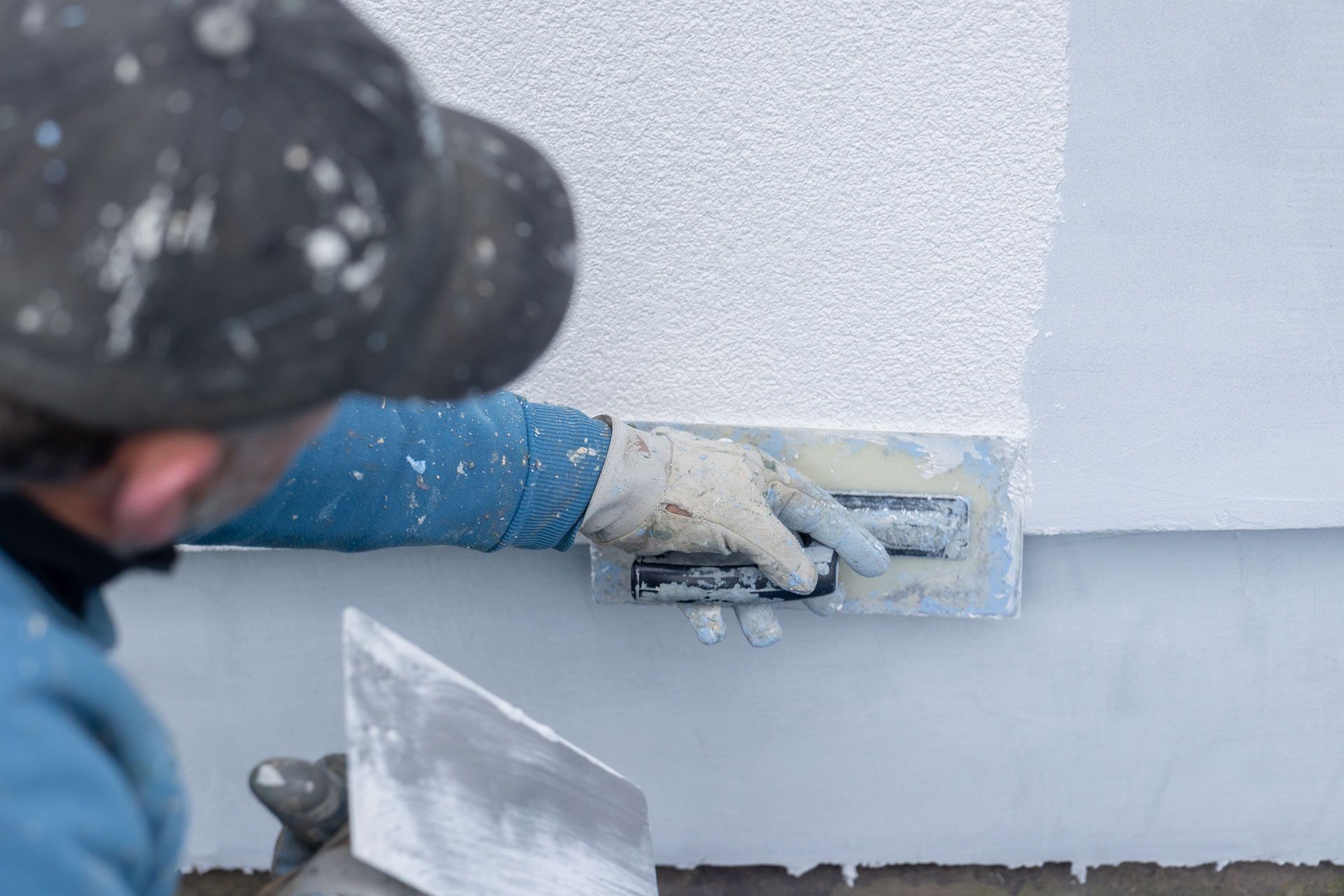 Worker smoothing white plaster on a wall with a trowel