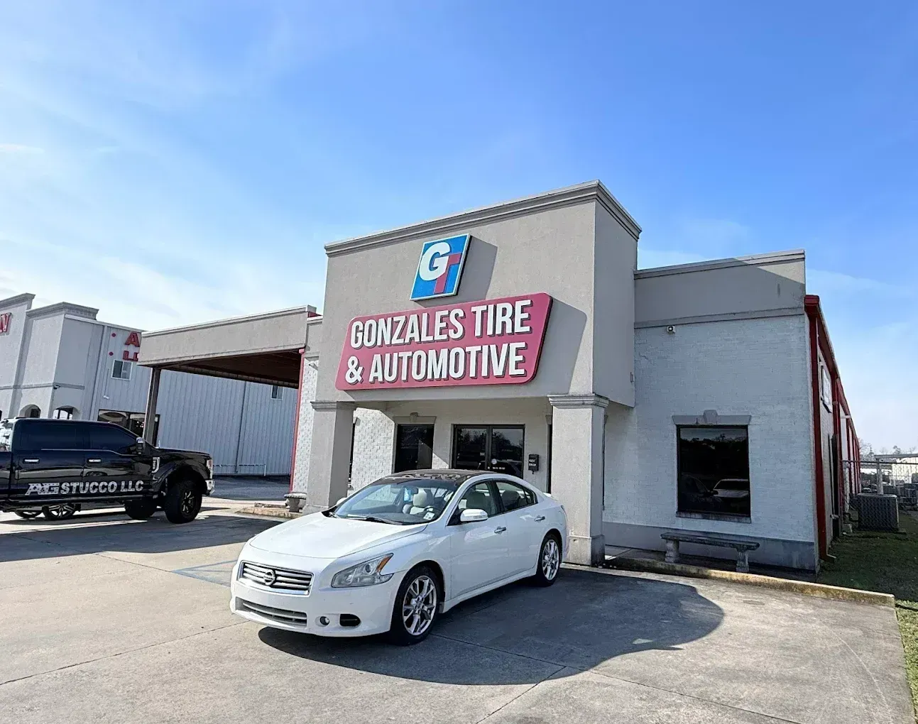 Gunz Auto Tire & Automotive storefront with a white sedan parked outside
