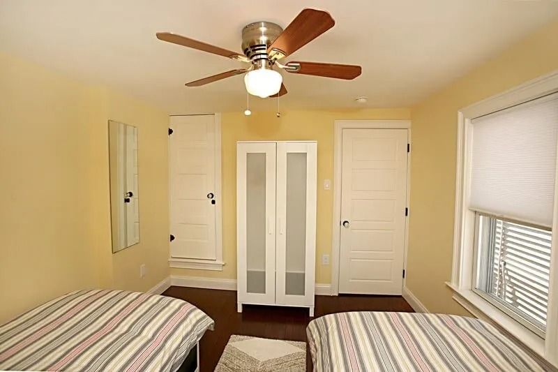 A bedroom with two beds and a ceiling fan