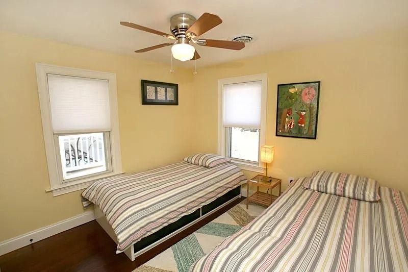 A bedroom with two beds and a ceiling fan