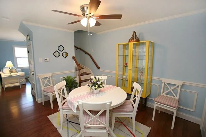 A dining room with a table and chairs and a ceiling fan