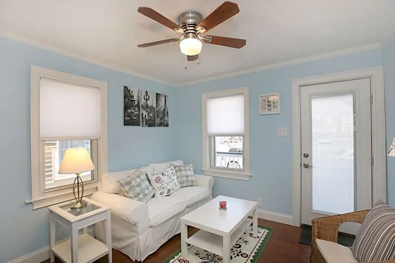 A living room with a couch , table , chair and ceiling fan.