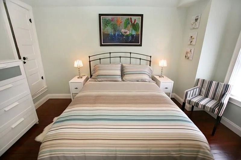 A bedroom with a bed , two nightstands , a chair and a painting on the wall.