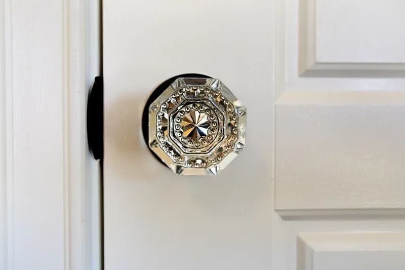 A close up of a door knob on a white door