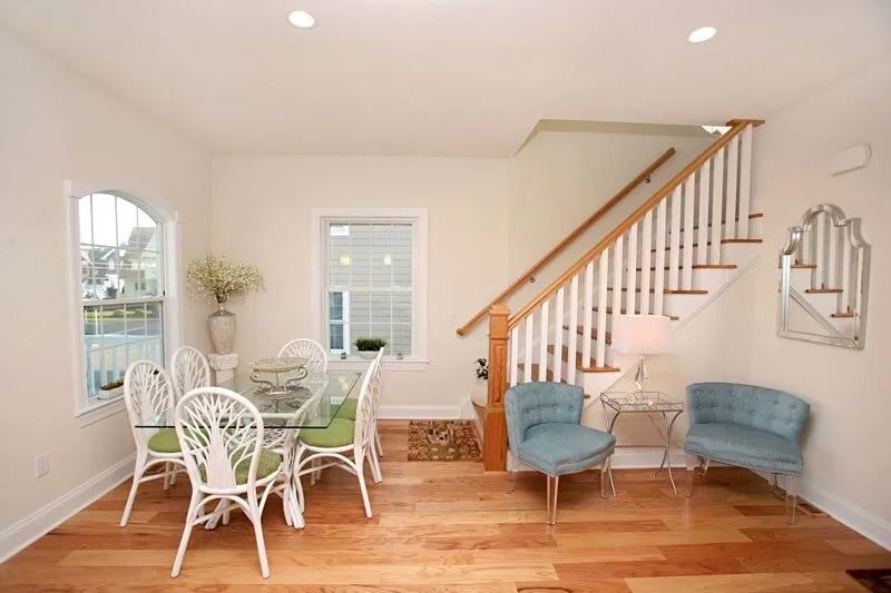 A dining room with a table and chairs and stairs leading up to the second floor.