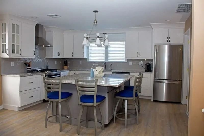A kitchen with white cabinets and a stainless steel refrigerator
