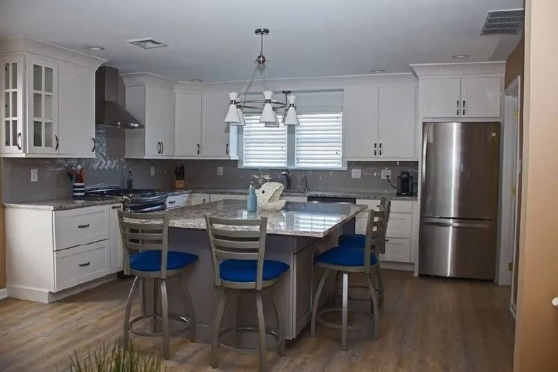 A kitchen with white cabinets and a stainless steel refrigerator