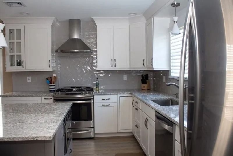 A kitchen with white cabinets , stainless steel appliances and granite counter tops.