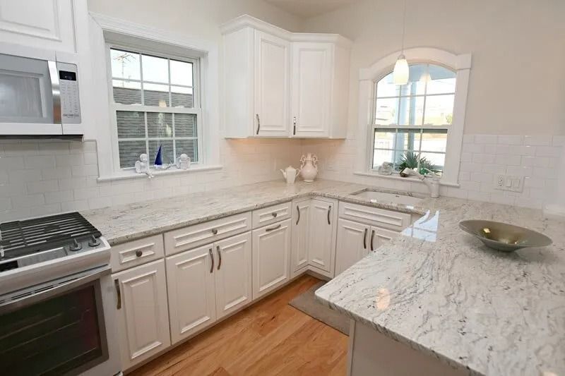 A kitchen with white cabinets and granite counter tops