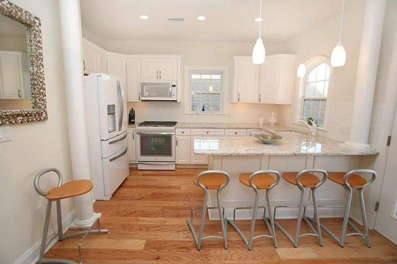 A kitchen with white cabinets and hardwood floors