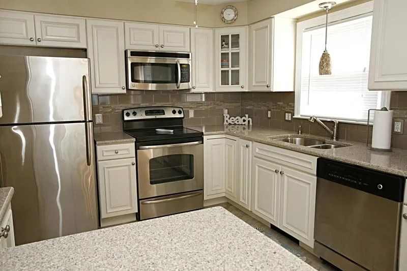 A kitchen with stainless steel appliances and white cabinets.