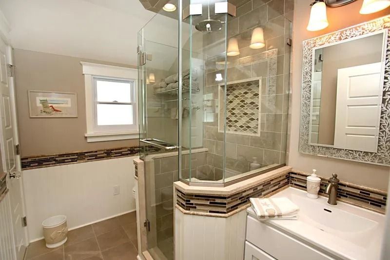 A bathroom with a walk in shower , sink , mirror and window.