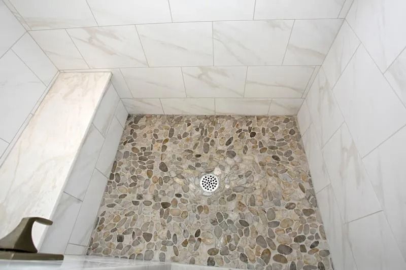 A walk in shower with a bench and a drain.