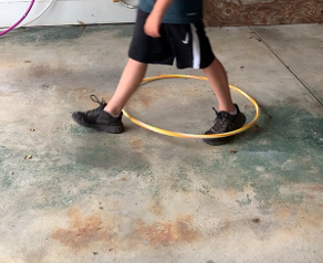 A person wearing nike shorts is walking around a yellow hula hoop