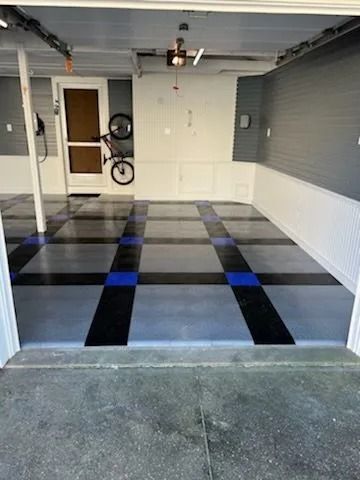 A bicycle is parked in a garage with a checkered floor.