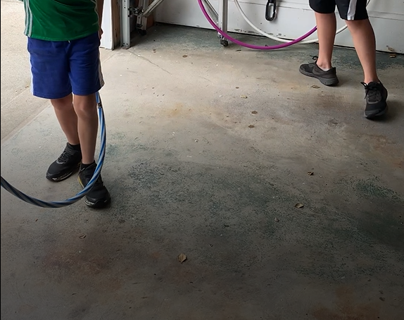 Two boys are playing with a jump rope in a garage