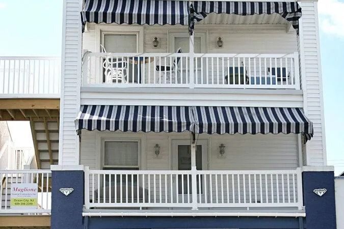 A white building with a black and white awning on the balconies.