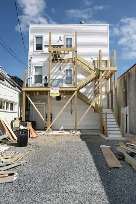 A white building with a wooden deck and stairs