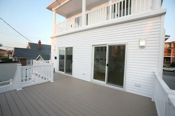 A large white house with a large deck and sliding glass doors.