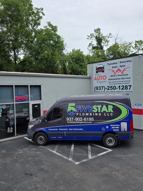 Blue Five Star Plumbing & Heating van parked outside a service shop with a red auto sign.