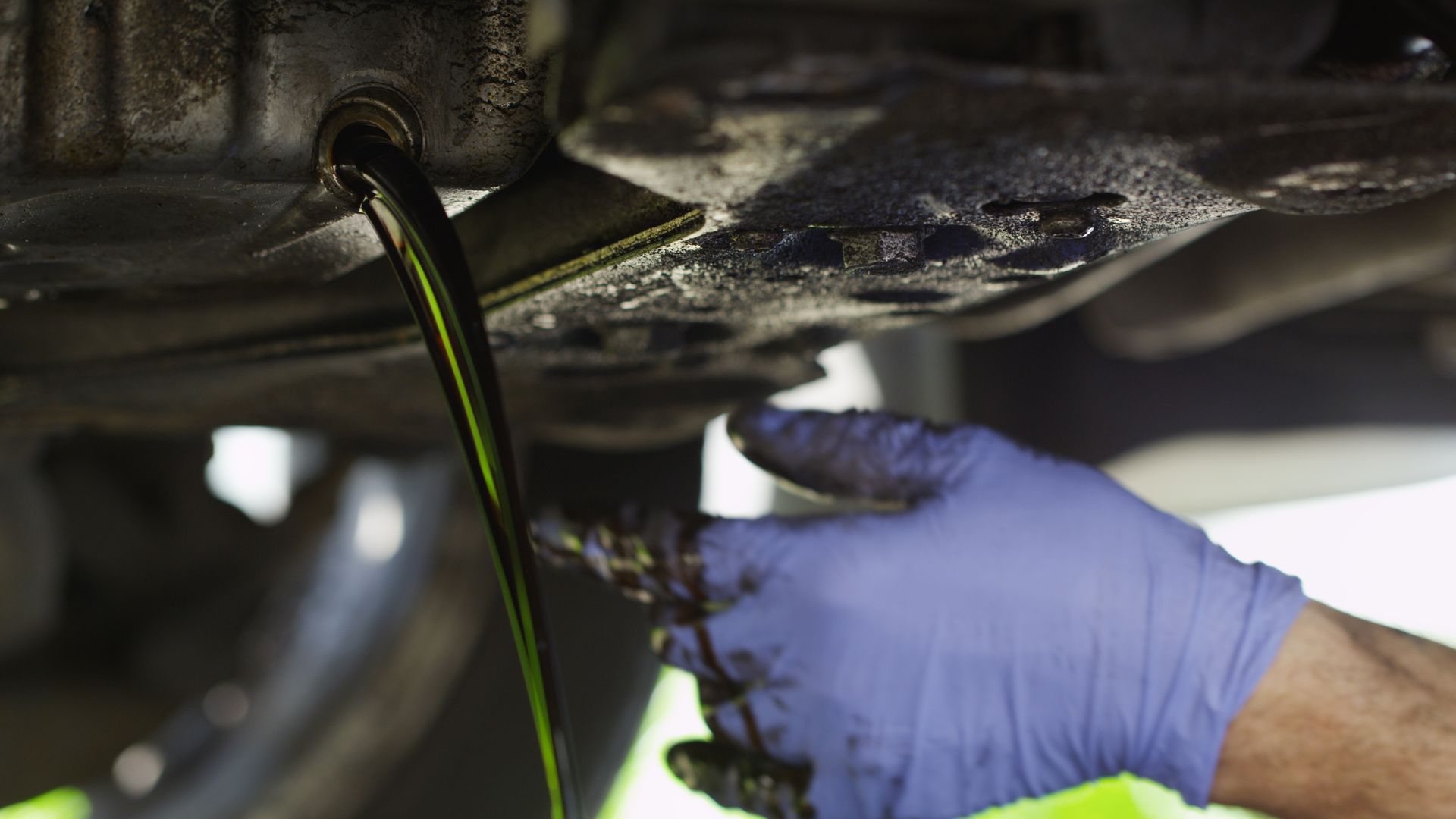 A mechanic draining oil from a car.