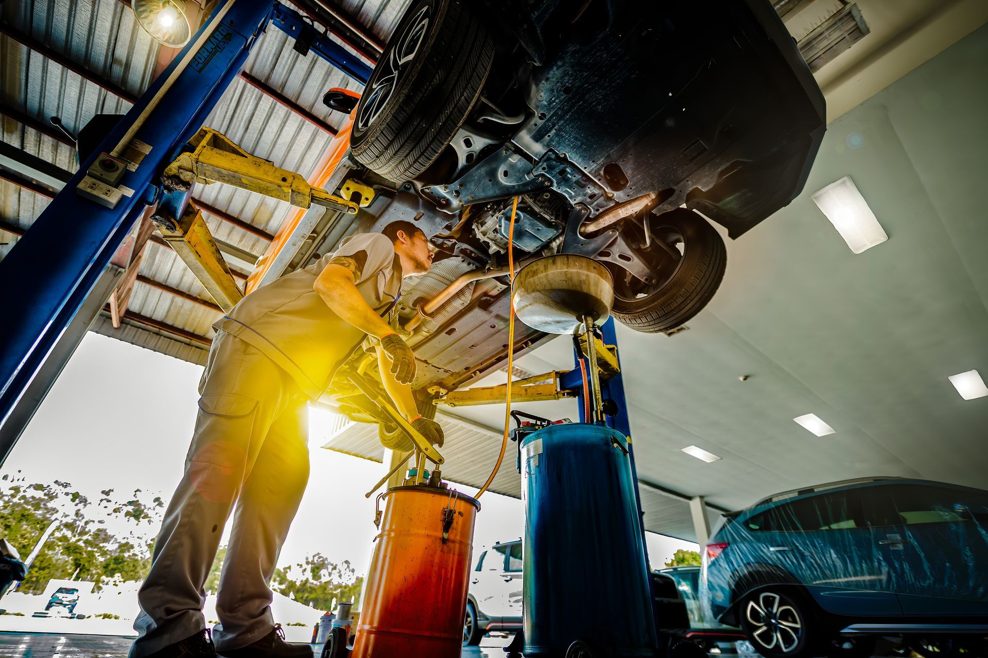 Low-angle view of a car undergoing maintenance by a professional technician at an auto shop.