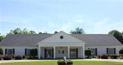 Single-story white house with gray roof, centered porch, and a manicured front lawn under a blue sky