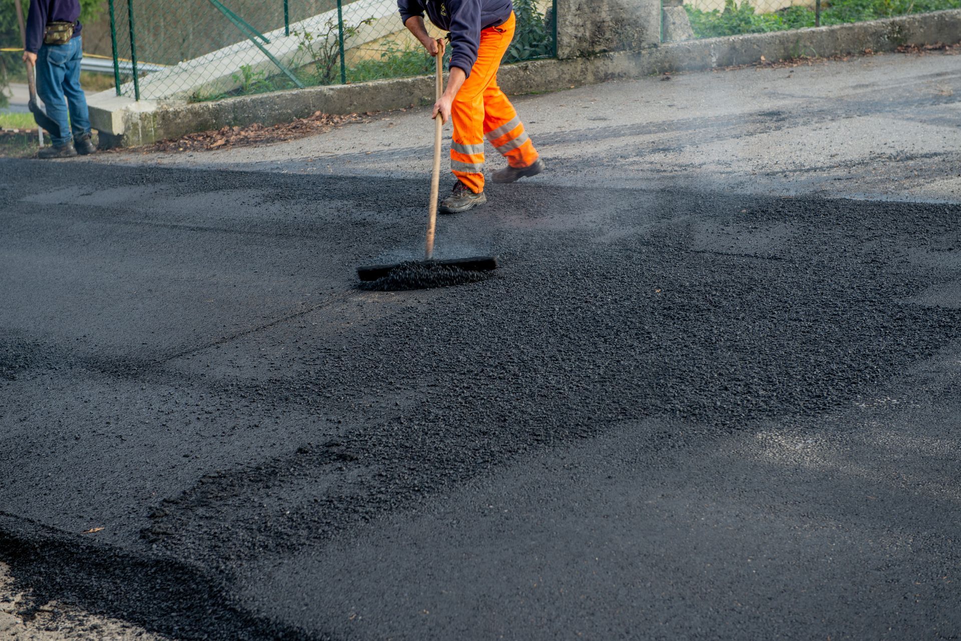 Paving crew spreading fresh asphalt on a driveway