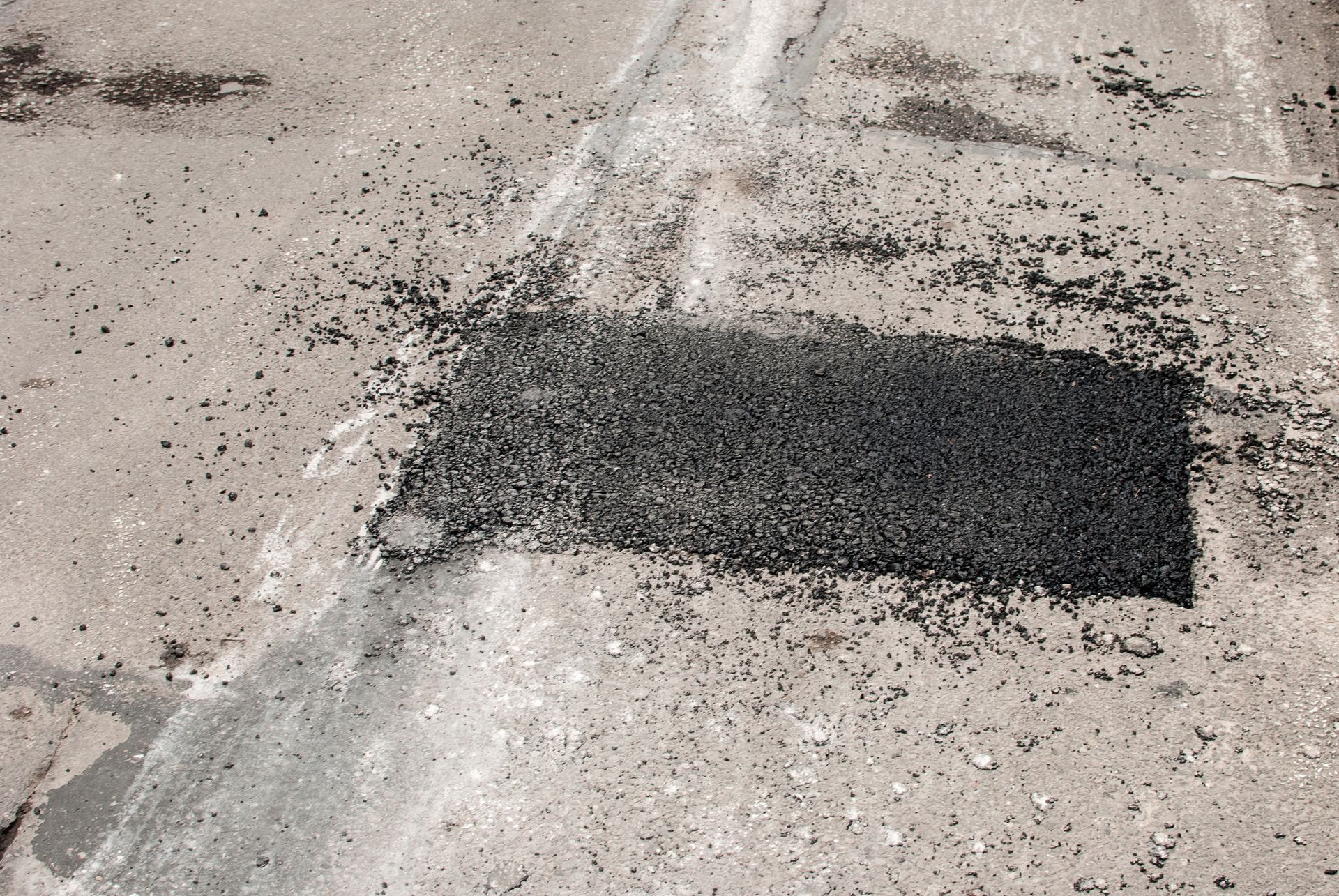 A square patch of asphalt has been recently placed on a road. A square patch of asphalt has been recently placed on a road.