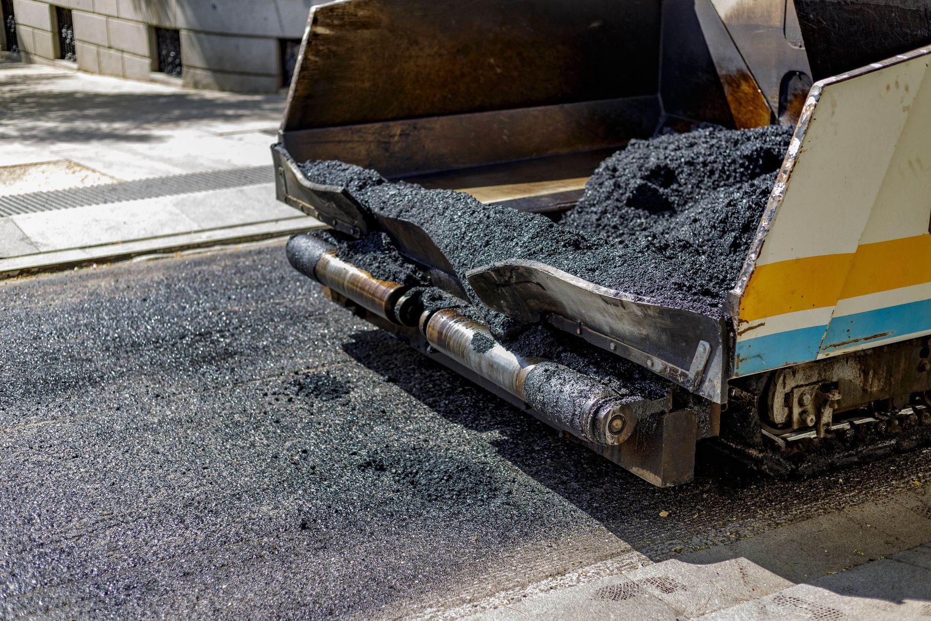 Asphalt Paver spreads asphalt on a road being paved. Asphalt Paver spreads asphalt on a road being paved.