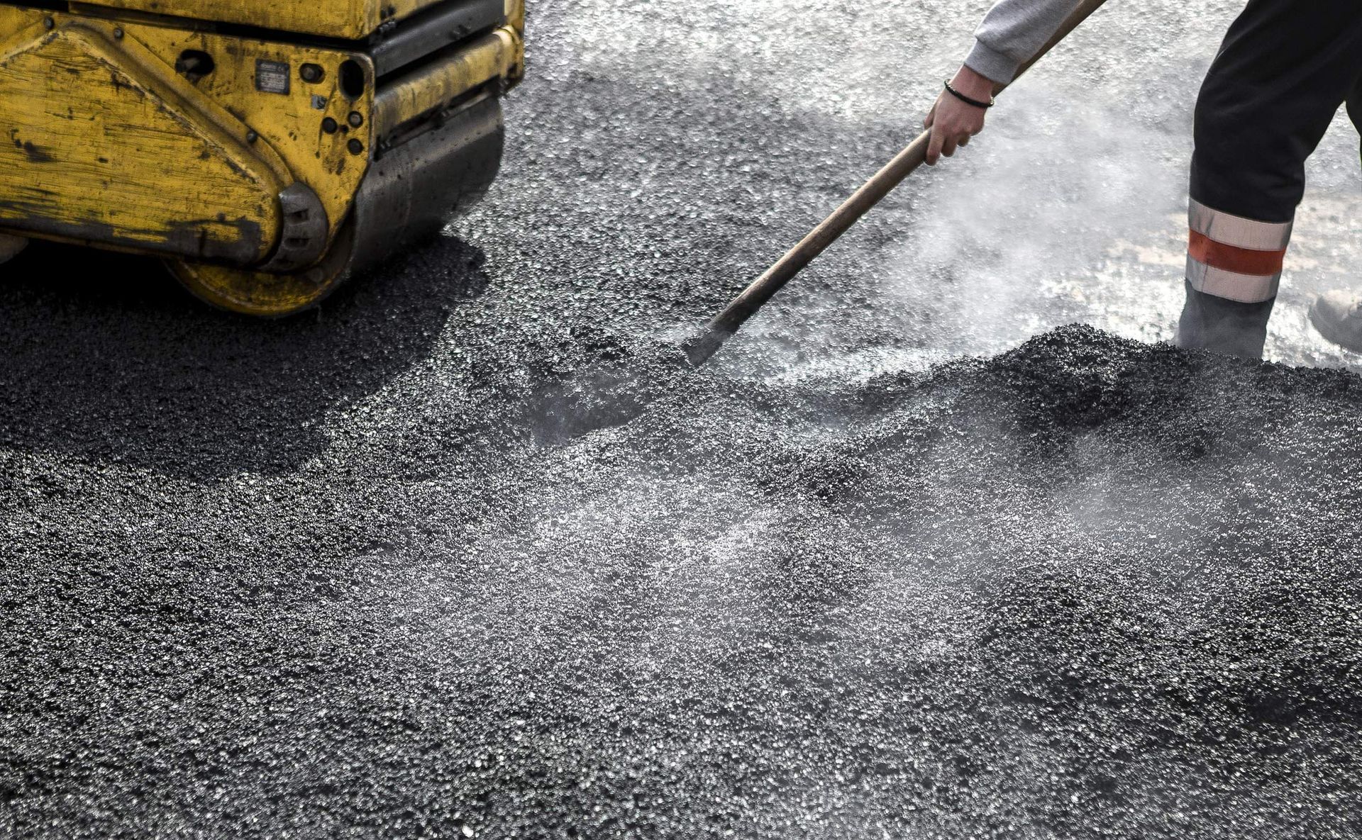 Close-up of an asphalt contractor service with a roller compacting the asphalt on a road. Close-up of an asphalt contractor service with a roller compacting the asphalt on a road.