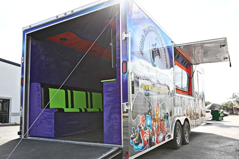 Gaming trailer with open back ramp and side door. Colorful exterior with seating inside.