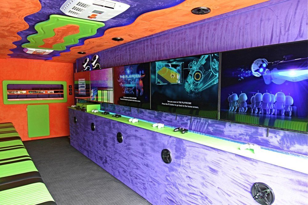 Inside of a brightly-colored game truck with multiple screens and game consoles along the purple wall.