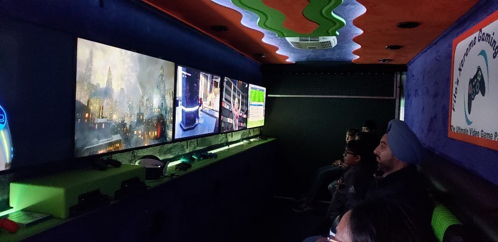Inside of a gaming truck with multiple screens. People are seated watching screens with games.
