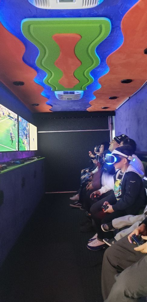 Inside a gaming truck, people play video games while wearing VR headsets.