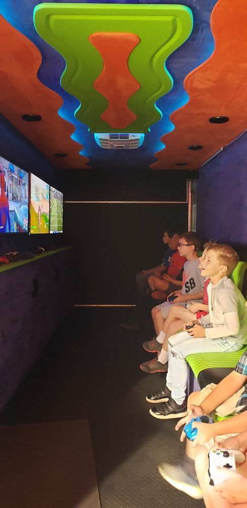 Children playing video games inside a colorful mobile gaming truck.