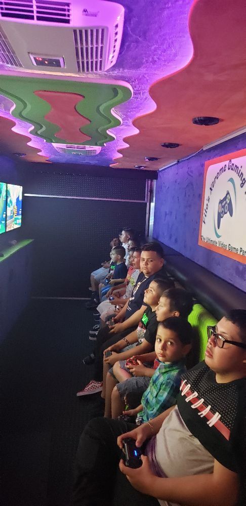 Children playing video games inside a colorful party truck.