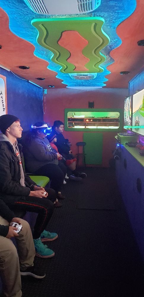 People playing video games inside a colorful, retro-styled gaming truck.