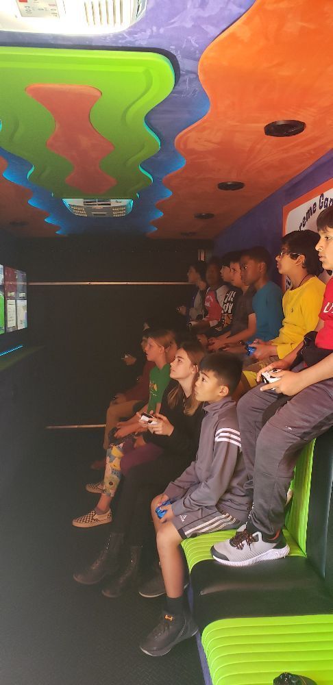 Children playing video games inside a colorful mobile gaming truck.