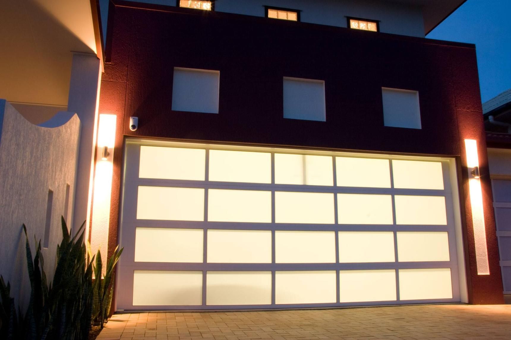 A Large White Garage Door Is Lit Up At Night — The Roller Door Man NQ In Portsmith, QLD