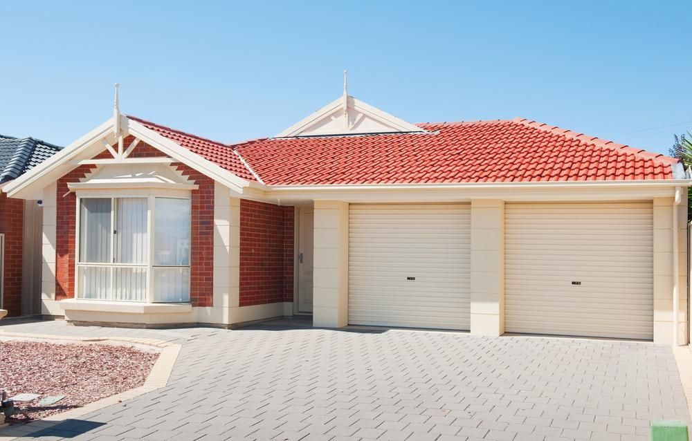 A House With A Red Roof And White Garage Doors — The Roller Door Man NQ In Portsmith, QLD
