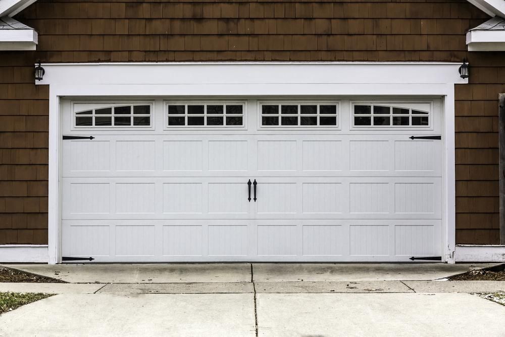 A White Garage Door Is On The Side Of A House — The Roller Door Man NQ In Portsmith, QLD